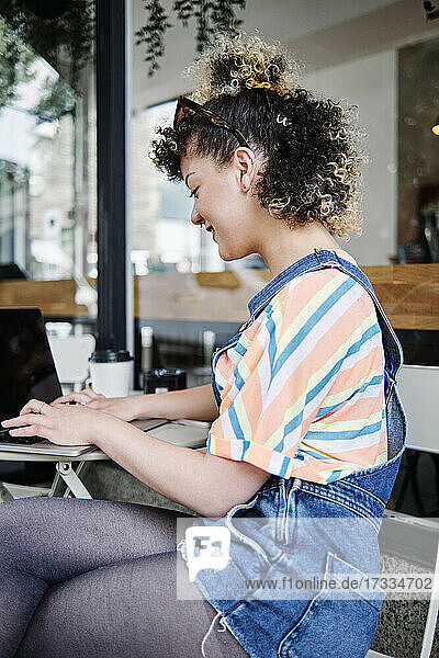 Woman using laptop at sidewalk cafe