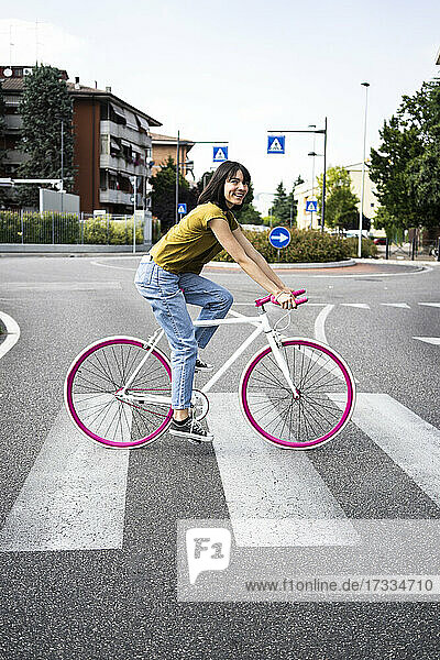 Woman crossing road while riding bicycle in city