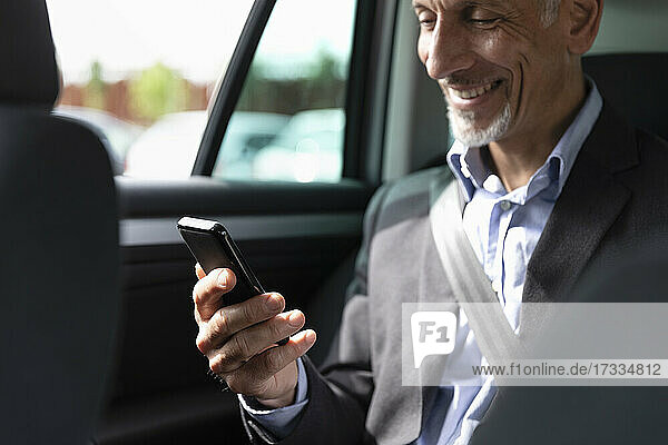 Männlicher Geschäftsmann benutzt sein Smartphone im Auto