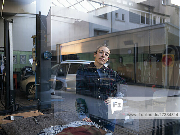Weiblicher Mechaniker in einer Autowerkstatt durch ein Fenster gesehen