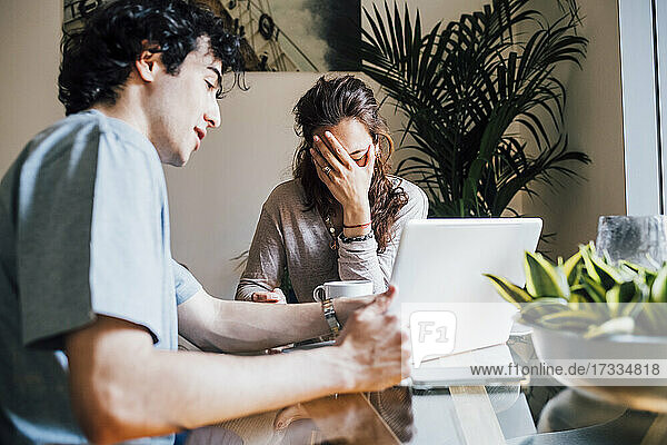 Boyfriend with laptop explaining to frustrated girlfriend at home
