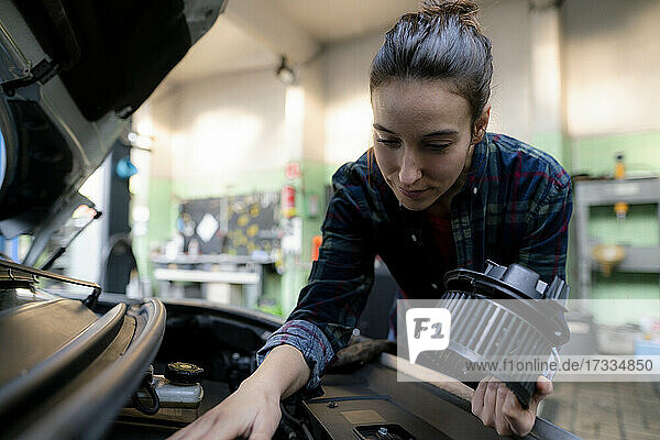 Ein weiblicher Mechaniker untersucht einen Automotor in einer Reparaturwerkstatt