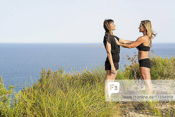 Female friends with eyes closed feeling heartbeats while standing together at cliff