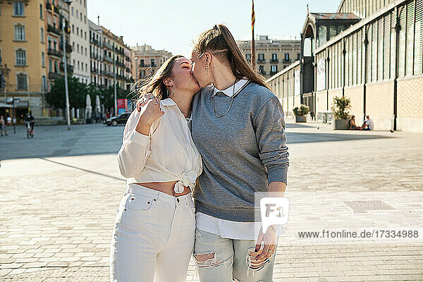 Lesbian couple kissing each other while walking in city