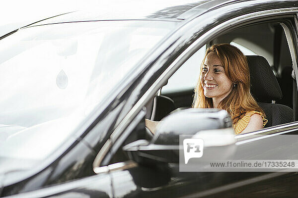 Lächelnde rothaarige Frau am Steuer eines Autos