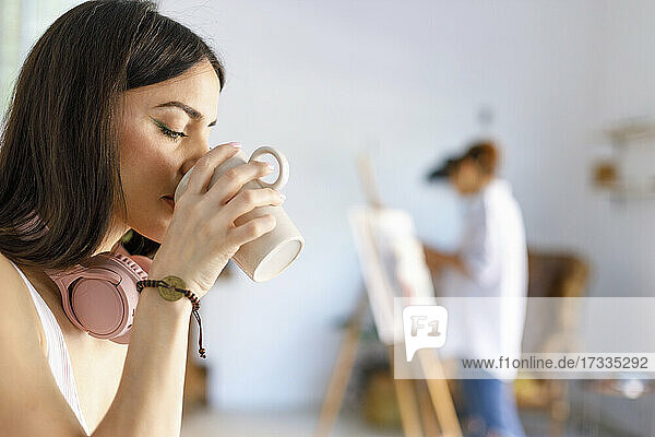 Frau trinkt Kaffee im Atelier eines Künstlers