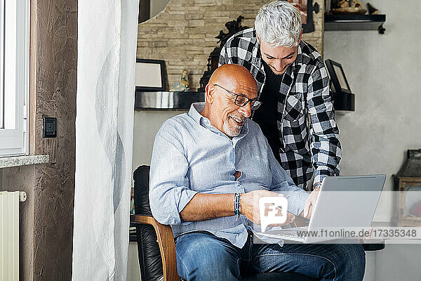 Father using laptop with son at home