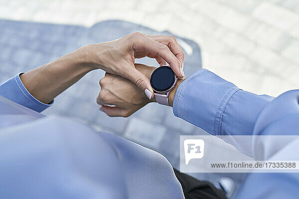 Geschäftsfrau  die eine intelligente Armbanduhr benutzt  während sie auf dem Gehweg steht