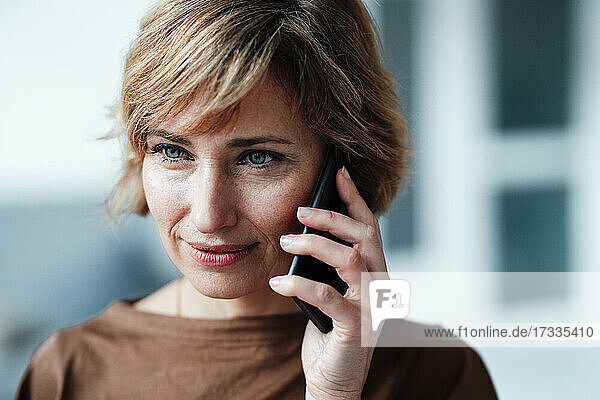 Geschäftsfrau  die im Büro mit einem Smartphone telefoniert