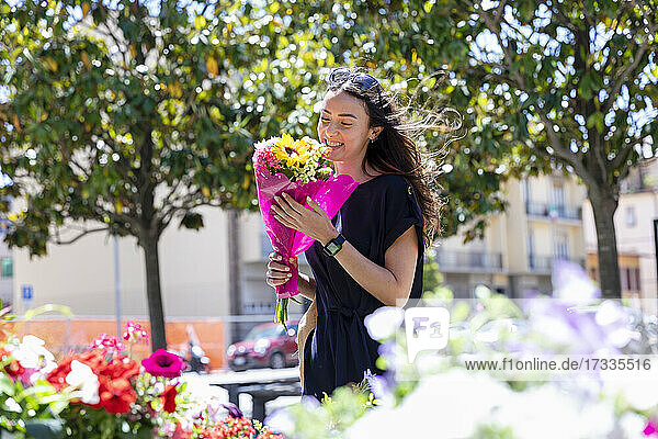 Lächelnde Frau mit Blumenstrauß in einem Blumenladen