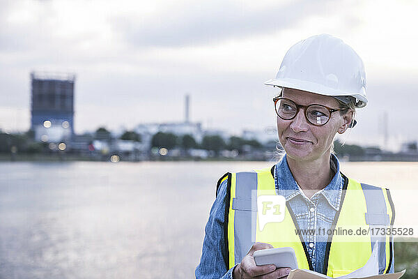 Lächelnde Arbeiterin  die ihr Smartphone in der Hand hält