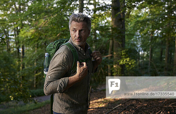 Mann mit Rucksack beim Wandern im Wald