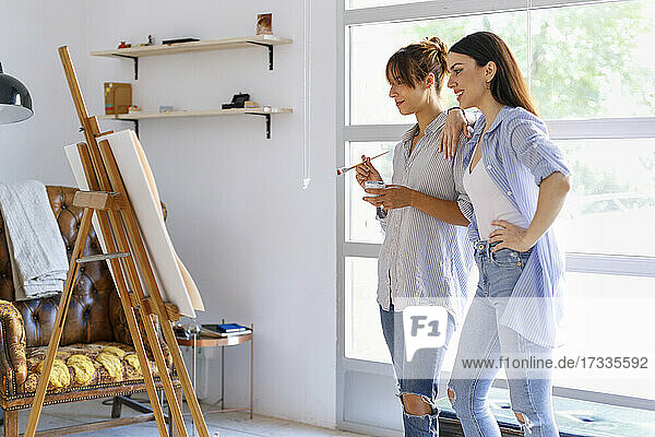 Künstlerinnen betrachten ein Gemälde  während sie zusammen in einem Kunstatelier stehen