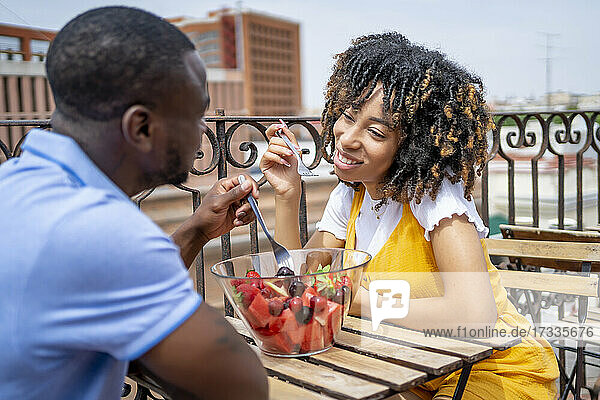 Mann und Frau essen Obstsalat  während sie auf dem Balkon sitzen