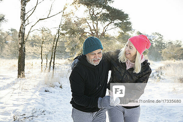 Fröhliches älteres Paar  das sich beim Spaziergang im Schnee an den Händen hält