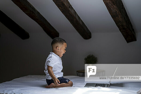 Junge schreit  während er auf dem Bett zu Hause auf seinen Laptop schaut