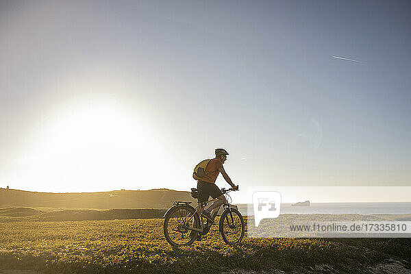 Männlicher Sportler fährt Mountainbike auf einer Wiese