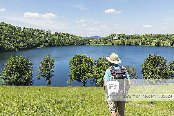 Senior hiker admiring view of Weinfelder Maar lake