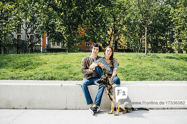 Paar sitzt zusammen mit einem Hund auf einer Bank