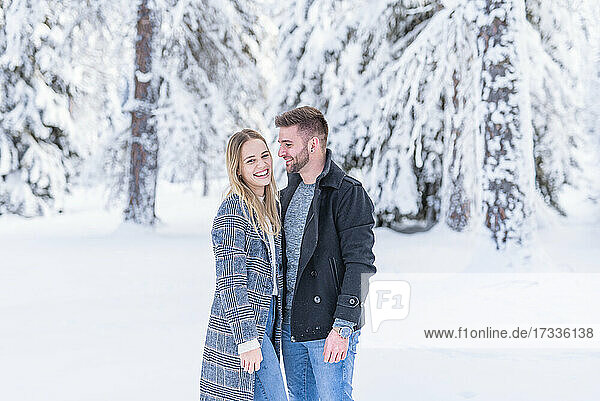 Lächelndes Paar im Schnee während des Winters