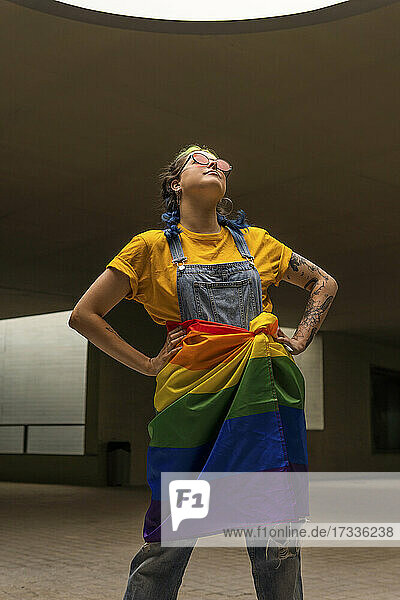 Hipster-Frau stehend mit Regenbogenflagge um die Taille gebunden