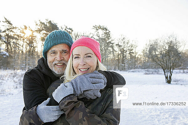Smiling senior man standing with arm around woman during winter