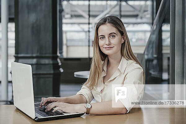 Schöne junge Geschäftsfrau sitzt mit Laptop in einem Cafe