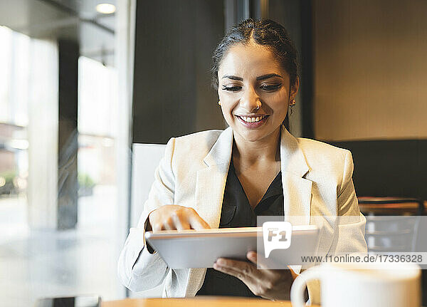 Berufstätige Frau benutzt digitales Tablet in einem Café