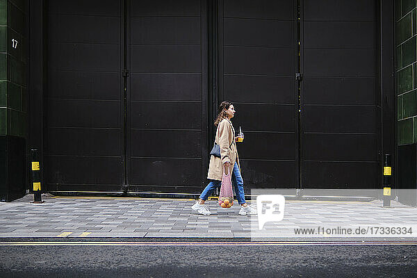 Junge Frau geht auf dem Fußweg durch schwarze Türen