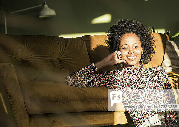 Young woman smiling while leaning on sofa at home