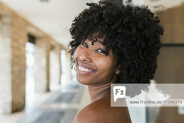 Smiling Afro woman looking over shoulder