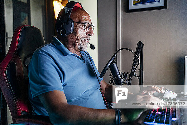 Älterer Mann beim Online-Streaming  während er zu Hause ein Videospiel spielt