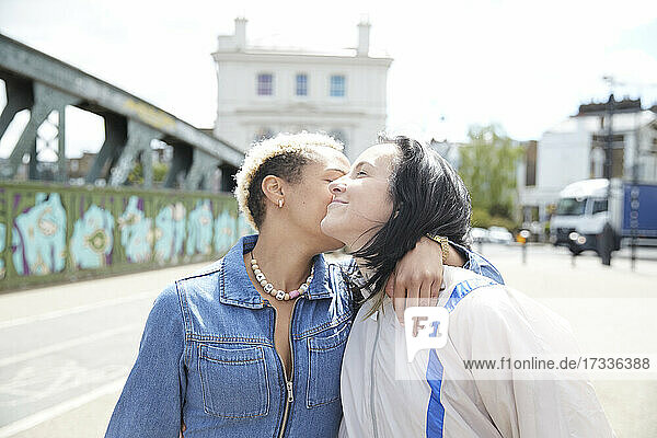 Lesbische Frau küsst Freundin an einem sonnigen Tag