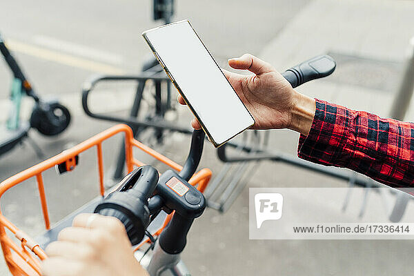 Frau entriegelt Fahrrad über Smartphone an einer Parkstation