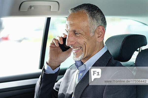 Smiling male business professional talking on mobile phone in car