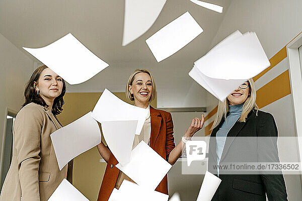 Happy businesswomen throwing documents enjoying in office together