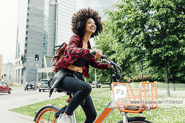 Cheerful woman riding bicycle in city