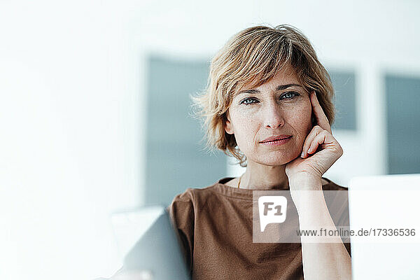 Businesswoman with hand on chin staring in office
