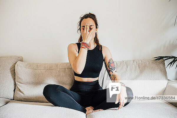 Frau übt Yoga im Schneidersitz zu Hause