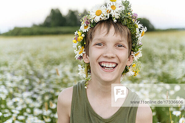 Junge mit Blumentiara lächelnd im Feld