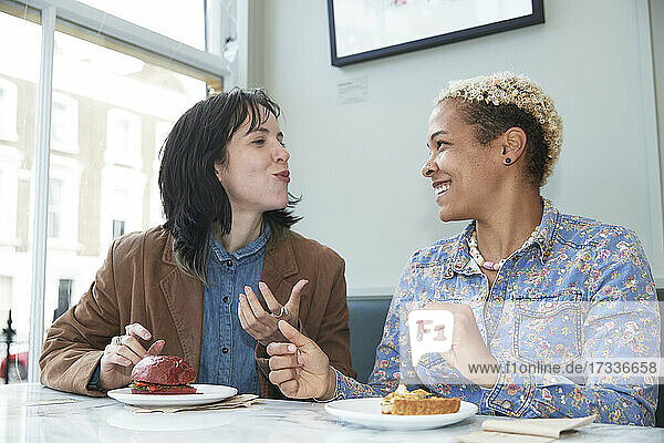 Glückliches lesbisches Paar isst Fast Food und sitzt zusammen in einem Café