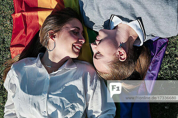 Lesbisches Paar  das sich auf der Regenbogenfahne liegend ansieht