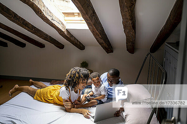 Vater und Mutter mit Sohn benutzen Laptop auf dem Dachboden zu Hause