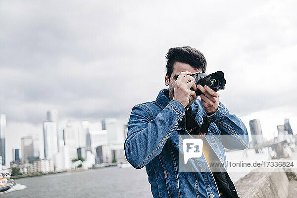 Mann beim Fotografieren mit Kamera an der Promenade