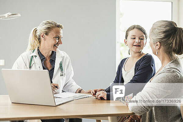 Tochter im Gespräch mit der Mutter  während sie beim Arzt im Büro sitzt
