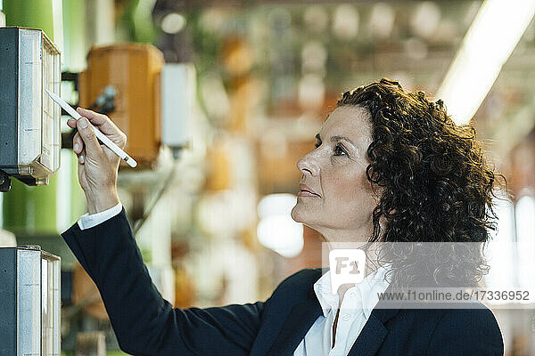 Businesswoman with digitized pen checking machine at workshop