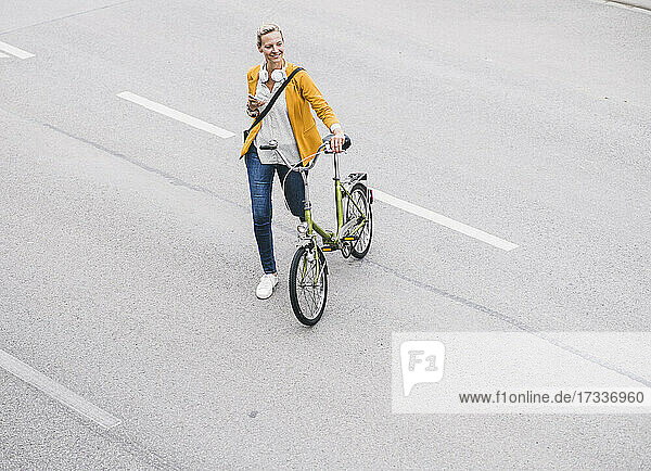 Lächelnde Frau mit Fahrrad auf der Straße