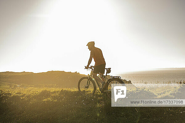 Mature male athlete riding mountain bike at sunset