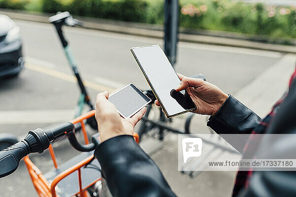 Frau mit Kreditkarte und Smartphone an einer Fahrradparkstation