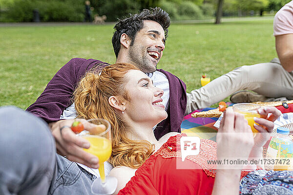 Glückliche Freunde mit Getränk beim Picknick im Park